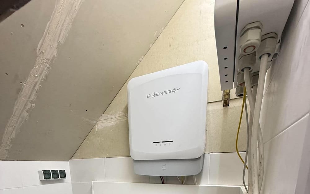 Falownik hybrydowy Sigenergy na ścianie i modułowy magazyn energii SigenStor 27 kWh w pomieszczeniu ze skosem